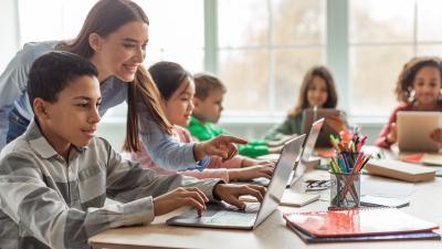 Students on computers with teacher helping