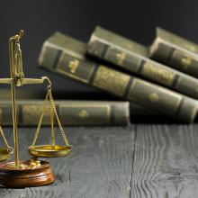 Gold law pendulum on wooden desk with old books in background